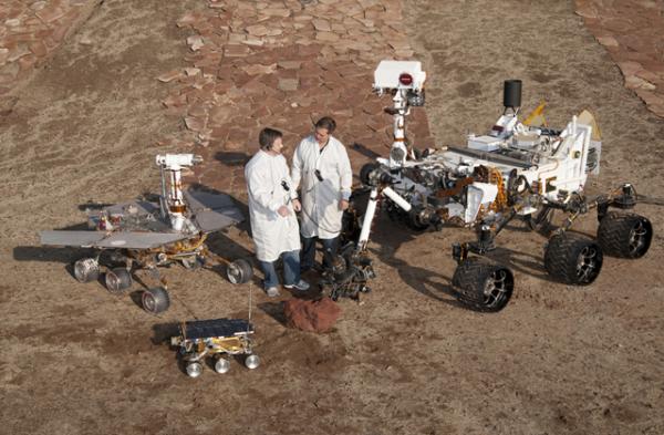 Три поколения марсианских роверов, разработанных в Лаборатории реактивного движения НАСА в Пасадине, размещены рядом на «марсианском» испытательном дворе.    Впереди по центру — запасной бортовой ровер Marie Curie, близнец первого марсохода Sojourner, который приземлился на Марсе в 1997 году в рамках проекта Pathfinder. Слева — работающая копия роверов-близнецов «Спирит» и «Оппортьюнити», приземлившихся на Марс в 2004 году. «Оппортьюнити» до сих пор работает на красной планете. Справа — тестовый образец нового ровера «Кьюриосити» в рамках нового проекта «Марсианская научная лаборатория» (Mars Science Laboratory Project’s Curiosity), который должен приземлиться на Марсе в августе 2012 года. Длина первого ровера Sojourner и его бортового близнеца Marie Curie — 2 фута (65 см). Длина роверов «Спирит» и «Оппортьюнити» — 5.2 футов (1.6 м). Длина нового ровера «Кьюриосити» — 10 футов (3 м). Photo Credit NASA/JPL