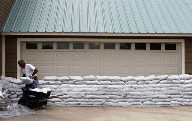 Даллас Матте сооружает дамбу из мешков с песком вокруг своего имения в Лугуетте, штат Луизиана, после того, как было объявлено, что шлюзы дамбы на канале "Морганса" будут открыты и его дому грозит наводнение. 11 мая 2011 г. Photo by David Grunfeld / Times-Picayune