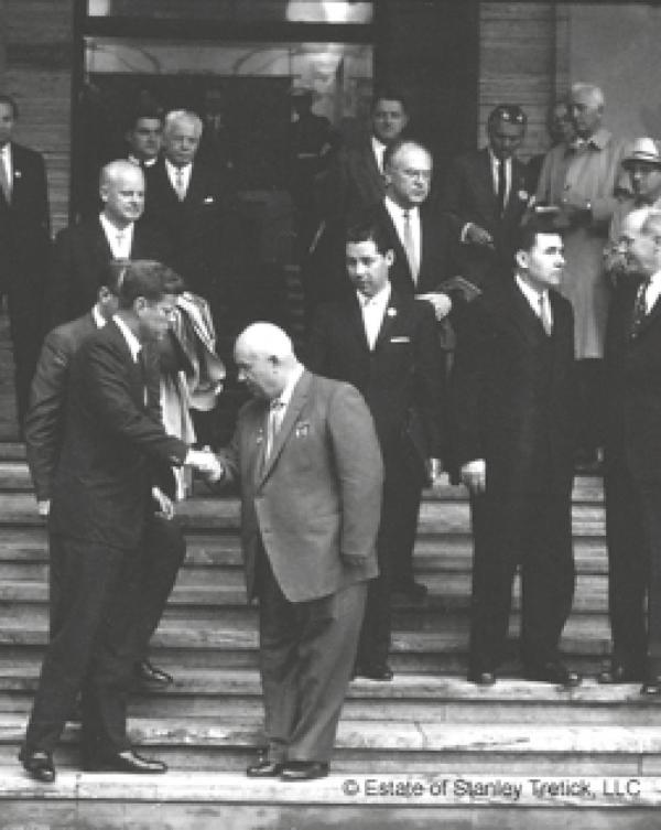 Никита Хрущев и Джон Кеннеди приветствуют друг друга рукопожатием во время двухдневного саммита в Вене в 1961 году. Виктор Суходрев стоит на ступеньках выше, непосредственно за спиной Хрущева. Справа от него — министр иностранных дел СССР Андрей Громыко беседует со своим американским коллегой, Госсекретарем Дином Раском.